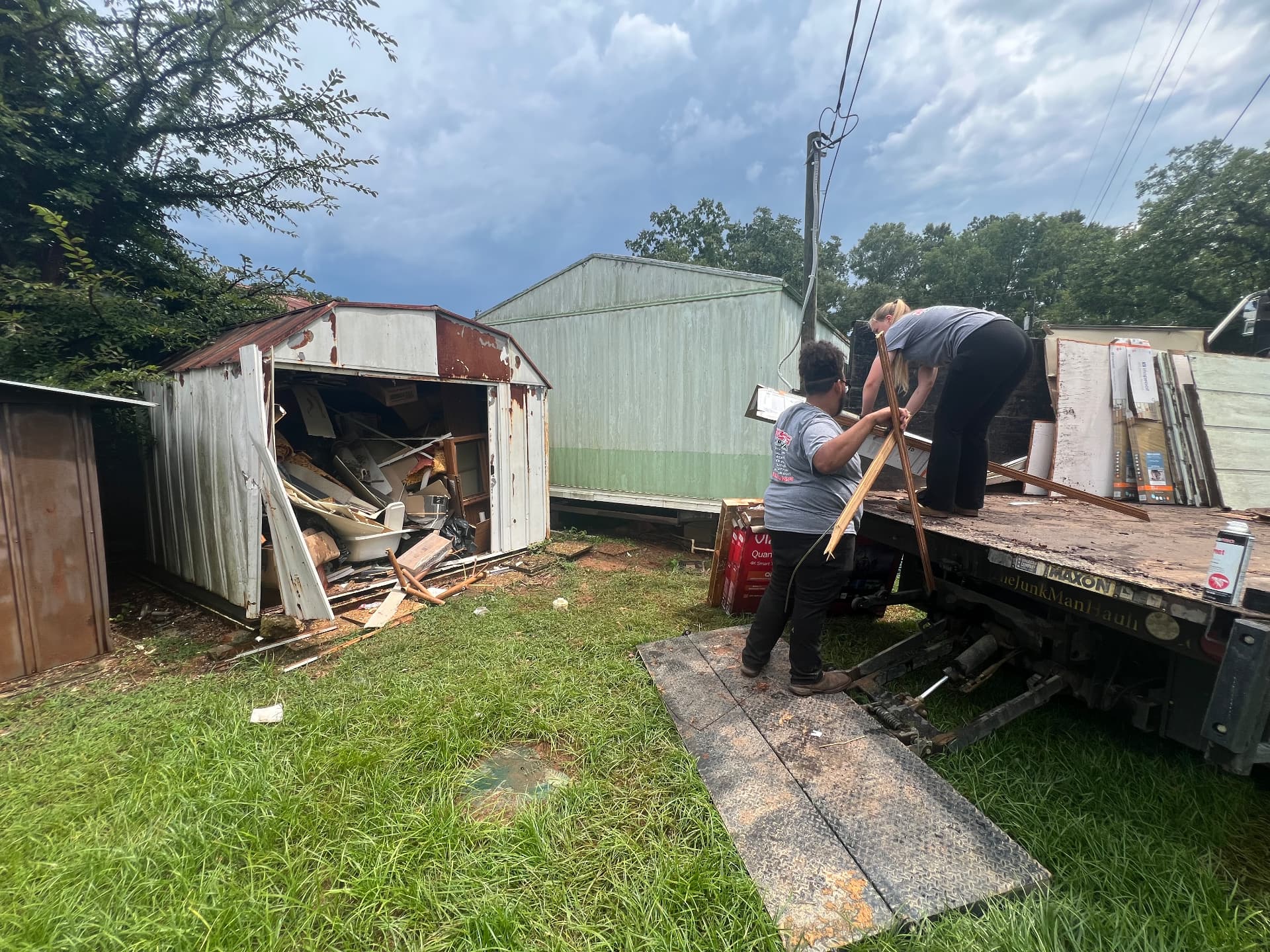 Crew tearing down a metal storage shed and loading the debris onto the dump truck