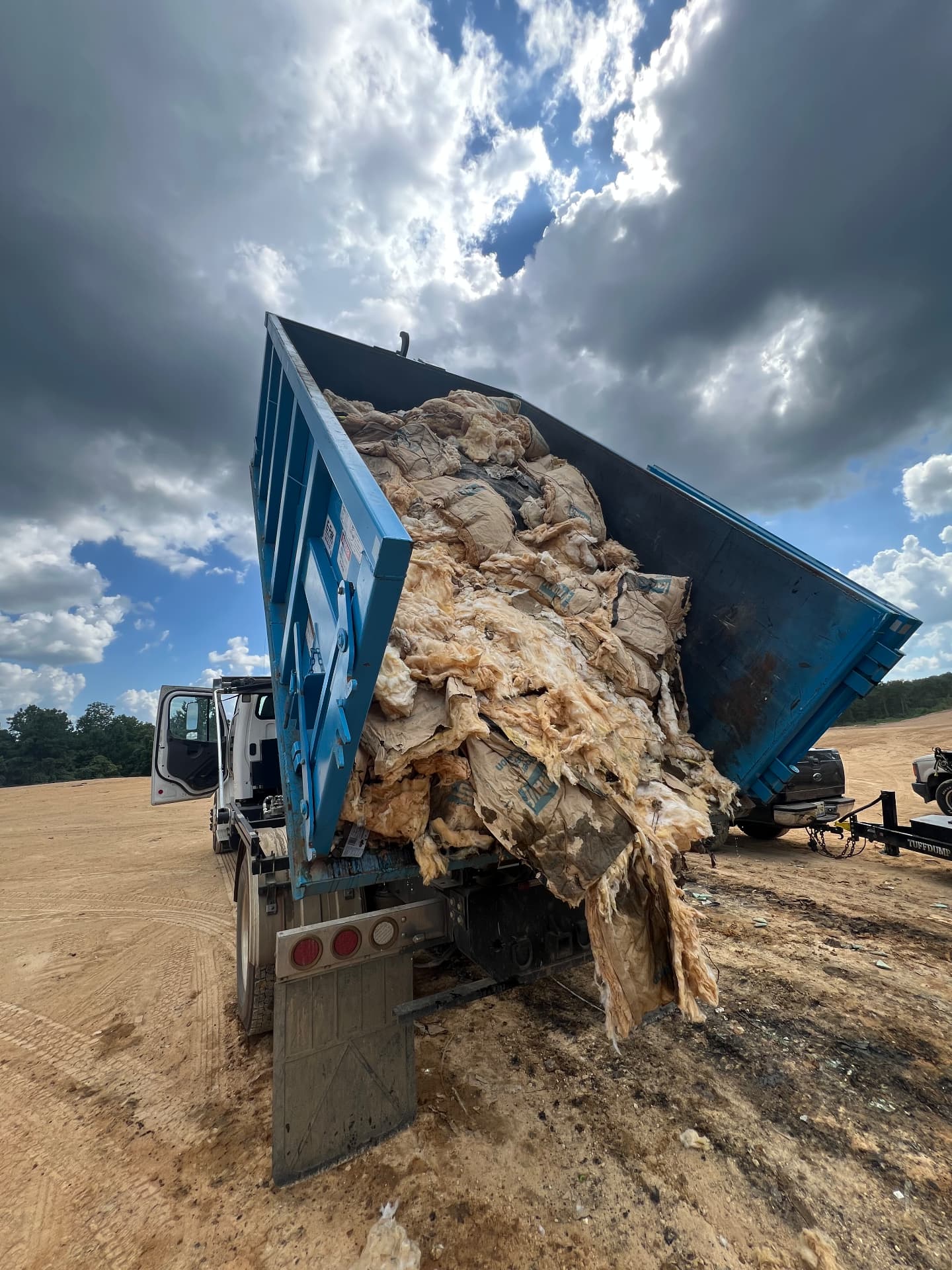 Dump truck offloading insulation and construction debris at the transfer site